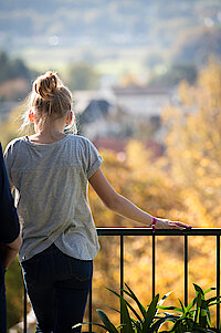 Ein Mädchen steht an einer Brüstung und blickt über das Rheintal