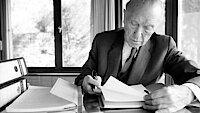 Konrad Adenauer sitzt am Schreibtisch und liest Akten