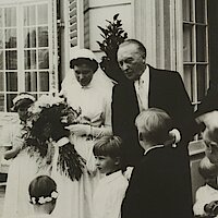 Konrad Adenauer mit seiner Tochter Lotte und mehreren Kindern. Sie trägt ein Brautkleid und hält einen Blumenstrauß in der Hand 