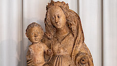 Muttergottes aus Lindenholz vor beigem Wandbehang