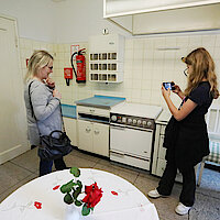 Zwei Frauen in einer Küche vor einem Herd, machen ein Foto mit dem Smartphone