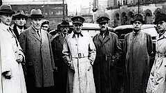 Adenauer und mehrere Personen in Mänteln oder Uniformen bei einem Rundgang durch Köln
