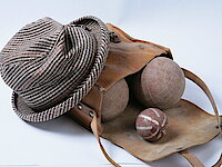 Ein karierter grau-brauner Pepita-Hut und eine Ledertasche mit Boccia-Kugeln