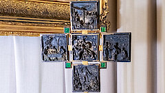 Auf einem Deckchen steht der lilafarbene Edelstein, darauf ist das verzierte Bronze-Kreuz befestigt.