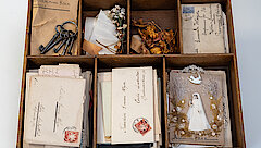 eine Holzkiste mit Briefen und Objekten